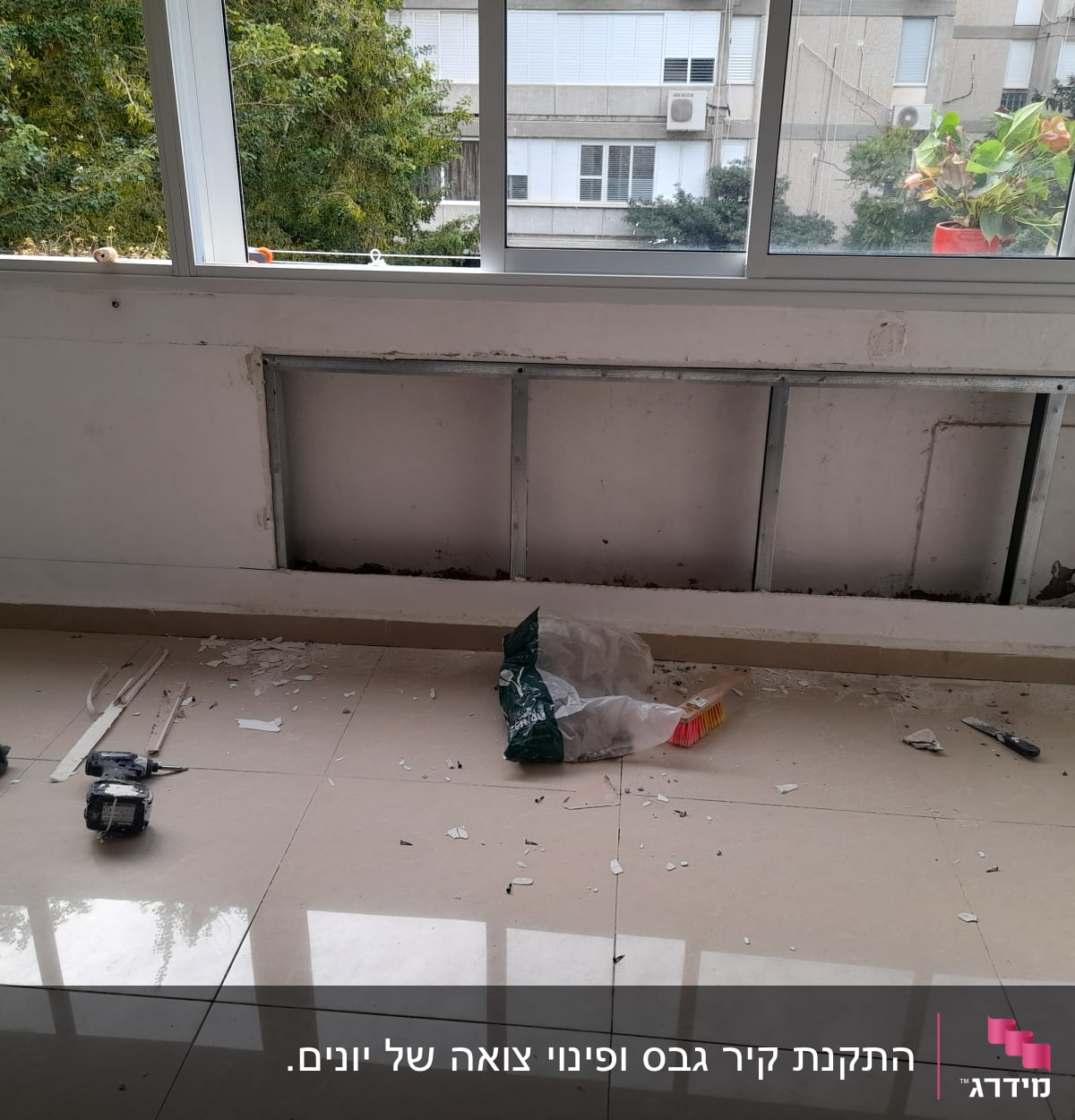 קיר גבס פתוח עם מסגרת מתכת וכלי עבודה על הרצפה